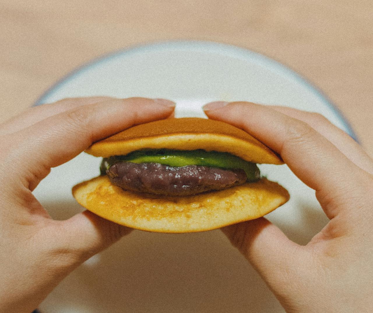 Hands holding a Japanese dorayaki filled with matcha and red bean, typical of Tokyo's culinary delights.