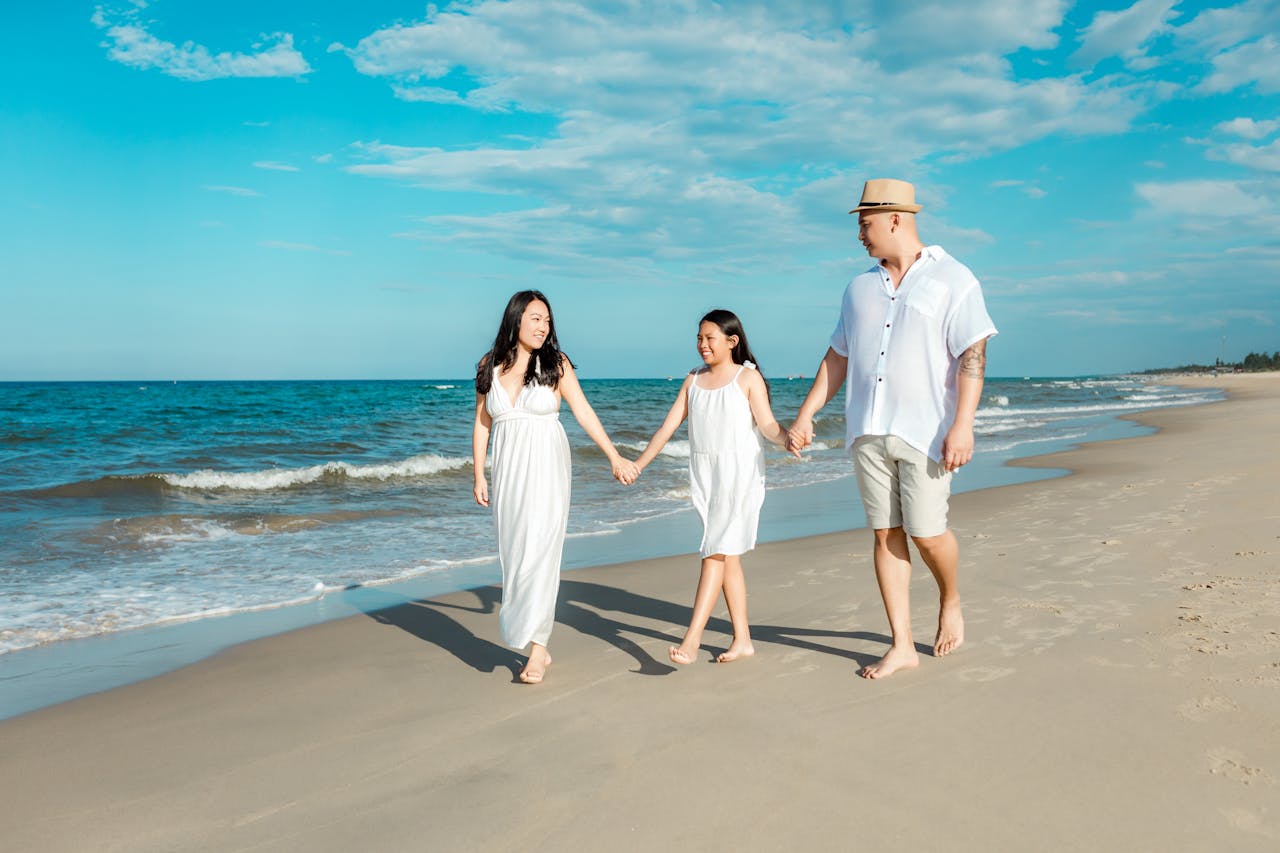 A happy family walking on Hội An's beach during summer, enjoying quality time together.